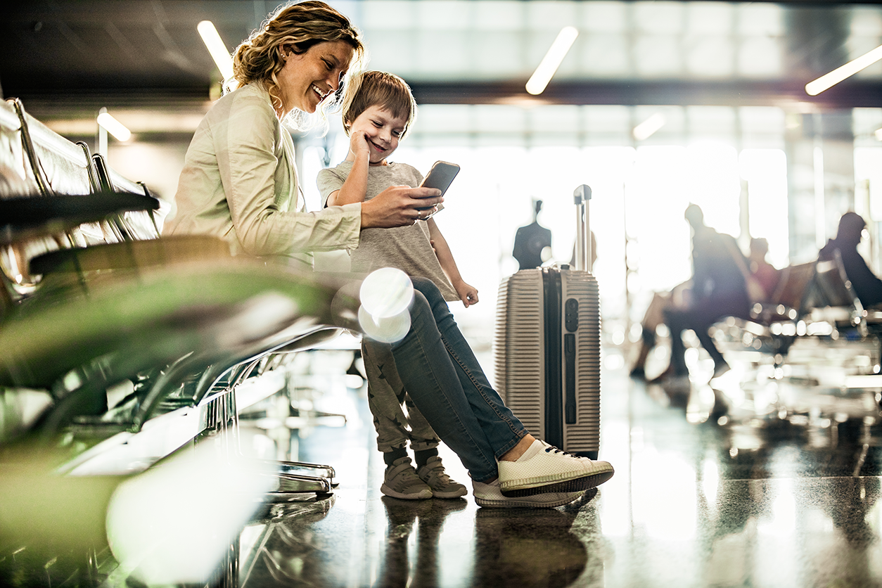 Mom and son look at travel itinerary while waiting at an airport