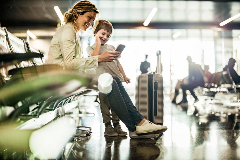 Mom and son look at travel itinerary while waiting at an airport