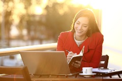 Woman sitting outside looking at computer - golden hour