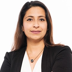 Nabila Mirza - headshot. She is staring at the camera slightly smiling, and crossing her arms confidently. She is wearing a black blazer with a white shirt
