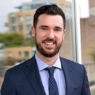 Nick Hearne headshot. He is wearing a dark blue suit with a dark blue tie.